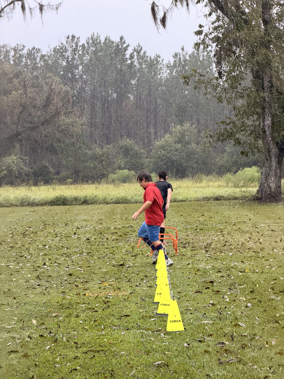 Two ORVIT students completing a soccer agility course during the rain